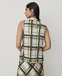 A woman in a sleeveless, high-neck, plaid top and matching skirt stands against a plain, light-colored background. carousel Product Image 2