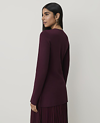 A woman in a burgundy sweater and pleated skirt stands against a plain, light-colored background. carousel Product Image 2