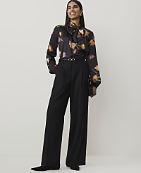 A woman in a floral blouse and black wide-leg pants stands against a plain, light background. carousel Product Image 1