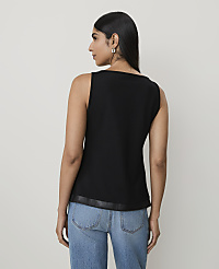 A woman in a black sleeveless top and blue jeans stands against a plain, light-colored background. carousel Product Image 2