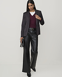 A woman in a patterned blazer, burgundy v-neck sweater, and black leather pants stands against a plain white background, holding a black clutch. carousel Product Image 3