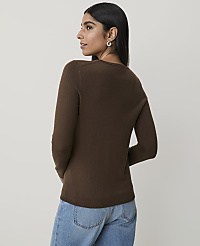 A woman in a brown sweater and blue jeans stands against a plain, light-colored background. carousel Product Image 2