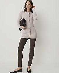 A woman in a beige cardigan and dark pants holds a clutch while standing against a plain background. carousel Product Image 4