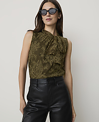A woman in a green lace top and black leather pants poses against a plain white background. carousel Product Image 1