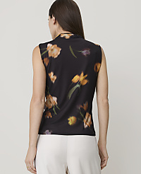 A woman in a black floral-print sleeveless top stands against a blurred background. carousel Product Image 2