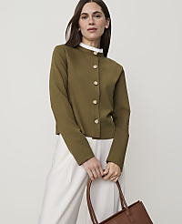 A woman in a green cardigan and white pants holds a brown tote bag in front of a plain background. carousel Product Image 1