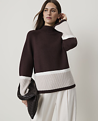 A woman in a burgundy sweater with cream and beige stripes holds a dark clutch in front of a plain background. carousel Product Image 1