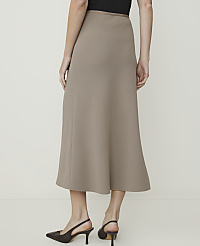 A woman in a taupe midi skirt and dark heels stands against a plain, light-colored background. carousel Product Image 3