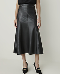 A woman in a black faux leather midi skirt and black heels stands against a plain, light-colored background. carousel Product Image 2
