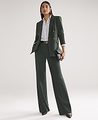 A woman in a dark green pantsuit stands against a plain, light gray background, holding a black clutch. carousel Product Image 5