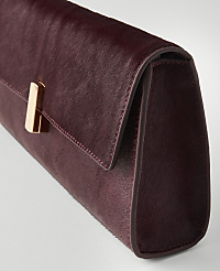 A burgundy clutch with a gold clasp rests on a white surface. carousel Product Image 2