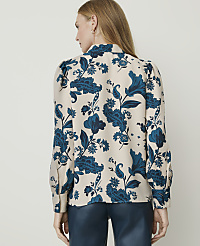 A woman in a cream-colored blouse with a blue floral pattern stands against a plain white background. carousel Product Image 2