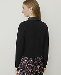 A woman in a black sweater with a leather collar and a patterned skirt stands against a plain, light-colored background. carousel Product Image 2