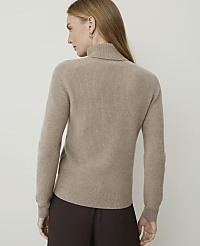 A woman in a beige turtleneck sweater stands against a plain, light-colored background. carousel Product Image 2