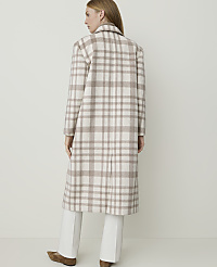 A woman in a plaid coat and white pants stands against a plain, light-colored background. carousel Product Image 2