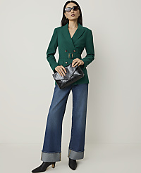 A woman in a green double-breasted blazer and wide-leg jeans holds a black clutch in front of a plain white background. carousel Product Image 3