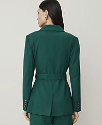 A woman in a green blazer stands against a plain, light-colored background. carousel Product Image 2