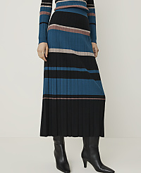 A person stands in black boots, wearing a pleated, striped skirt and matching top against a plain, light background. carousel Product Image 2