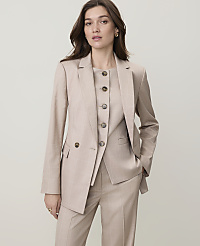 A woman in a beige suit stands against a plain, light-colored background. carousel Product Image 1