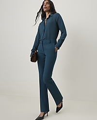 A woman in a teal pantsuit with a brown clutch stands against a plain white background. carousel Product Image 1