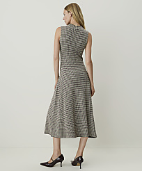 A woman in a sleeveless houndstooth dress and dark heels stands against a plain, light-colored background. carousel Product Image 2
