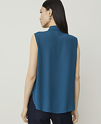 A woman in a teal sleeveless top and dark jeans stands against a plain, light gray background. carousel Product Image 2