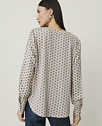 A woman in a patterned blouse stands against a plain, light-colored background. carousel Product Image 2