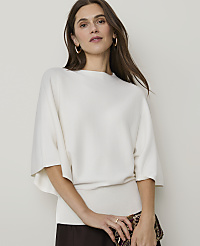 A woman in a cream-colored sweater and dark skirt poses against a plain, light background. carousel Product Image 1