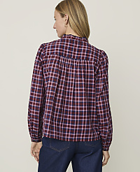 A woman in a maroon and pink plaid blouse stands against a plain, light-colored background. carousel Product Image 2