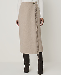 A beige wrap skirt with fringe detailing is worn over dark boots against a plain white background. carousel Product Image 2