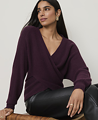 A woman in a plum-colored wrap sweater and black leather pants sits against a plain, light background. carousel Product Image 3