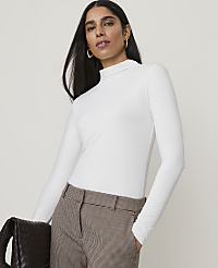 A woman in a white turtleneck and plaid pants holds a dark woven bag in front of a plain background. carousel Product Image 1