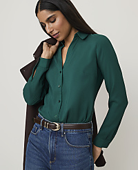 A woman in a green blouse and jeans stands against a plain background, with a brown jacket draped over her shoulder. carousel Product Image 1