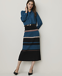 A woman in a teal blouse and a striped pleated skirt stands against a plain white background. carousel Product Image 3