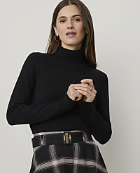 A woman in a black turtleneck and plaid skirt stands against a plain background. carousel Product Image 1