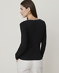 A woman in a black long-sleeved shirt and white pants stands against a plain, light gray background. carousel Product Image 2