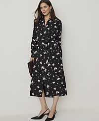A woman in a black floral dress and black heels stands against a plain, light-colored background, holding a burgundy clutch. carousel Product Image 1