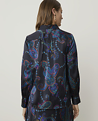 A woman in a dark, patterned blouse stands against a plain background. carousel Product Image 2