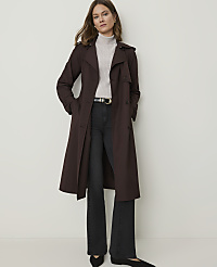 A woman in a brown trench coat and black flared jeans stands against a plain white background. carousel Product Image 1
