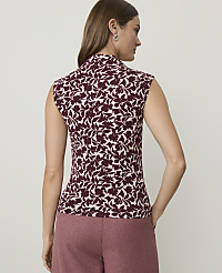 A woman in a floral top and pink pants stands against a plain background. carousel Product Image 2