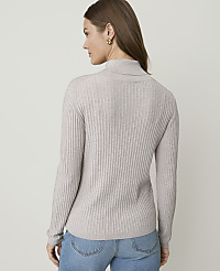 A woman in a light gray ribbed turtleneck sweater and blue jeans stands against a plain, light gray background. carousel Product Image 2