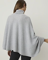 A woman wearing a light gray turtleneck poncho stands against a plain, light gray background. carousel Product Image 2