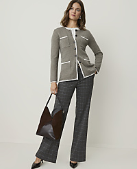 A woman in a grey cardigan and plaid pants stands against a plain background, holding a brown handbag. carousel Product Image 3