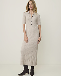 A woman in a beige cable-knit midi dress and dark boots stands against a plain, light-colored background. carousel Product Image 1