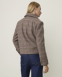 A woman in a brown and pink plaid jacket and dark jeans stands against a plain, light-colored background. carousel Product Image 2