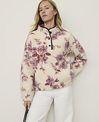 A woman in a cream-colored floral fleece pullover stands against a plain, light-colored background. carousel Product Image 1