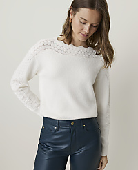 A woman in a cream-colored sweater and teal pants stands against a plain, light background. carousel Product Image 1