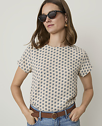 A woman in a patterned top and sunglasses stands against a plain background. carousel Product Image 1