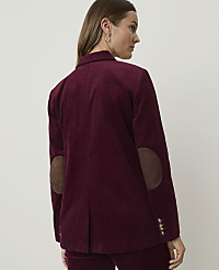 A woman in a burgundy corduroy blazer with suede elbow patches stands against a plain, light-colored background. carousel Product Image 2