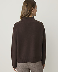 A woman in a brown turtleneck sweater and plaid pants stands against a plain, light gray background. carousel Product Image 2